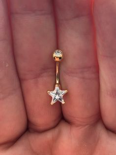 a person is holding a gold nose ring with a star design on the middle one