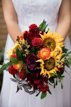 a bride holding a bouquet of sunflowers and other flowers