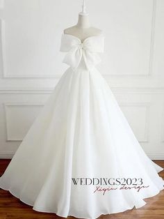 a white wedding dress with a big bow on the back