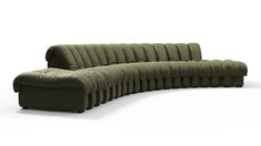 a large green couch sitting on top of a white floor next to a black chair