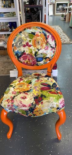 an orange chair with flowers painted on it in a room full of shelves and other items