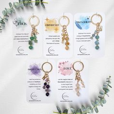 four keychains with different colored stones on them and some green leaves in the background