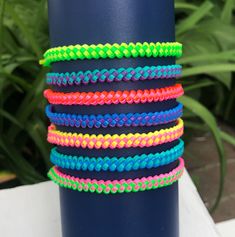 a stack of colorful bracelets sitting on top of a blue vase next to a plant