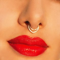 a woman's face with a nose ring on top of her nose and red lipstick