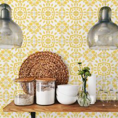 a shelf with jars, bowls and vases sitting on it next to two lamps