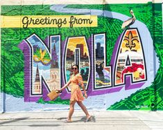 a woman walking past a colorful wall with the word'greetings from indiana'painted on it