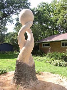 a large white sculpture sitting on top of a tree stump in front of a house