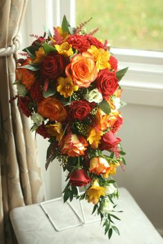 a bouquet of flowers sitting on top of a white bench next to a window with curtains