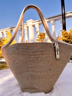 a straw bag with a tag hanging from it's side sitting on a bed