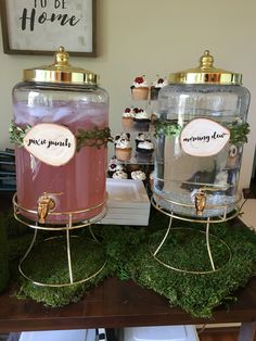 two large jars filled with cupcakes sitting on top of a moss covered table