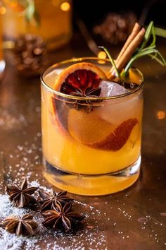 a drink with an orange and cinnamon garnish on the rim next to star anise