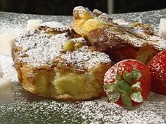 two pieces of french toast and some strawberries on a silver plate with powdered sugar