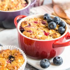 blueberry cobbler in a red casserole dish with muffins on the side