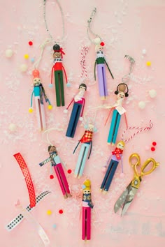 some colorful pencils and scissors are on a pink surface with confetti around them