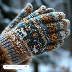 a person's hand wearing a knitted mitt with deers and snowflakes on it