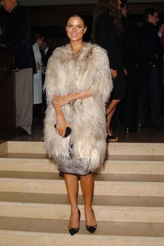 a woman in a fur coat standing on some steps