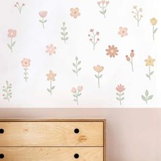 a dresser sitting next to a wall with flowers painted on it