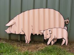 a pig and her baby are standing in front of a metal wall that is painted pink