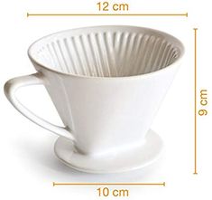 a white coffee cup sitting on top of a saucer next to a measuring tape