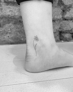 a small flower tattoo on the ankle is shown in this black and white photo,