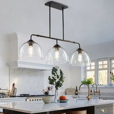 a kitchen island with stools and lights hanging over it