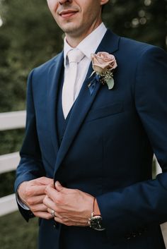 a man in a blue suit and flower boutonniere