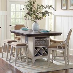 a dining room table with four chairs and a wine rack on the center island in front of it