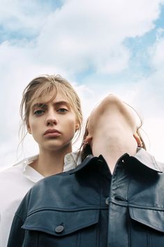 a woman in white shirt standing next to a man with black jacket on his shoulders