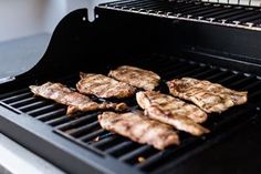 steaks are being cooked on the grill with tongs