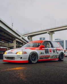 a white and red car parked in front of an overpass