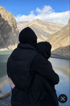 a person wearing a hooded jacket looking out over a mountain lake