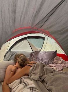 a woman laying in bed with her head on the pillow and sleeping bag next to her