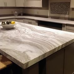 a marble counter top in a kitchen next to a bowl of fruit on the counter