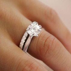 a woman's hand with a diamond ring on top of her finger and an engagement band