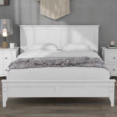 a white bed sitting on top of a wooden floor next to a night stand and dresser