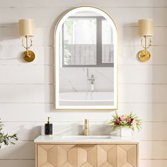 a bathroom vanity with a mirror above it and flowers on the counter top next to it