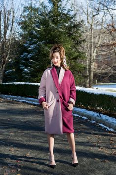 a woman wearing a pink coat and black dress