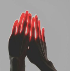 two hands with red lights on their palms against a gray background, in the air