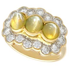 A stunning vintage 2.19 carat cat's eye chrysoberyl and 0.96 carat diamond, 18 karat yellow and white gold cocktail ring; part of our diverse gemstone jewelry collections. This stunning, fine and impressive vintage cabochon cut cat's eye chrysoberyl ring has been crafted in 18k yellow gold with an 18k white gold setting. The Victorian style scalloped edged design is ornamented with three cabochon cut cat's eye chrysoberyls, bezel set horizontally to the center of the cluster arrangement. The cen Yellow Gold Dress, White Gold Dress, Gold Cocktail Ring, Gold Cocktail, Victorian Rings, Gemstone Jewellery, Dress Rings, Three Stone Rings, Gold Dress