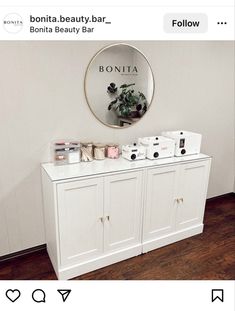 a white dresser sitting next to a mirror on top of a wooden floor in front of a wall