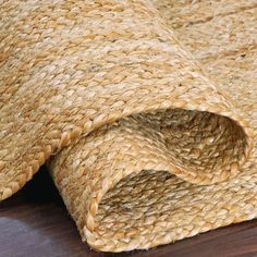 a close up view of a rug on a wooden floor, with the end section partially covered in jute