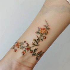 a woman's arm with flowers on it and leaves coming out of the wrist