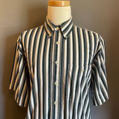 "You are viewing an excellent Vintage Men's Cotton Short Sleeve Shirt by Bugle Boy c1990. This great looking shirt is made of a medium weight cotton fabric in vertical stripes in putty, green, black and white. Details include button down collar, 7 button placket (with original translucent tan plastic buttons), patched left chest pocket, 11\" short sleeves and curved hem at waist. Dates from likely the very early 1990s. Retains original maker's label at neckline (Bugle Boy) and fabric content tag Striped Cotton Shirt With Short Sleeves, Classic Cotton Short Sleeve Shirt, Striped Collared Short Sleeve Cotton Shirt, Classic White Cotton Short Sleeve Shirt, Striped Cotton Collared Short Sleeve Shirt, Vintage Striped Cotton Shirt, Mens Cotton Shorts, White Details, Mens Oxfords