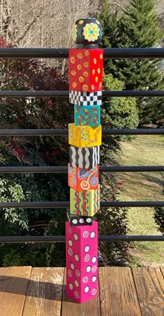 a stack of brightly colored dices sitting on top of a wooden deck next to trees