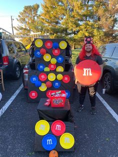 a man holding up a frisbee in front of some games on the parking lot