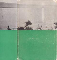 an old book with green pages and black and white images on the cover, in front of a body of water