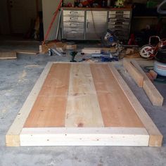 an unfinished bed frame in a garage with tools on the floor and other items around it