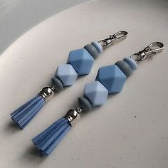 three blue and grey hexagonal beads with tassels on a white plate