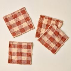 four red and white checkered napkins sitting on top of each other in front of a white wall