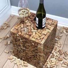 a wine bottle and glass on top of a block of corks that are laying on the floor